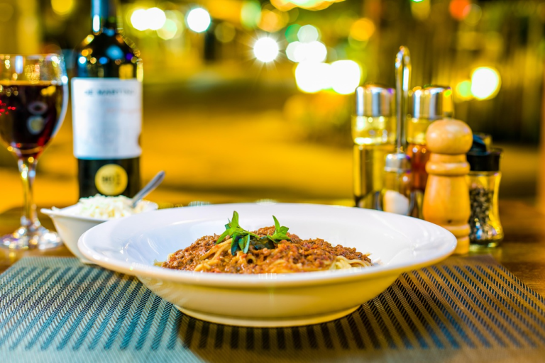 A cozy dinner table with a plate of pasta, a glass of wine, and warm seasonings — the perfect setting for easy family comfort meals made with love.