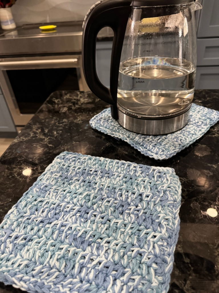 Double-thick crochet hot pad under a kettle on a kitchen counter