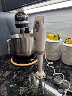 Immersion blender used in everyday kitchen cooking on a dark granite countertop