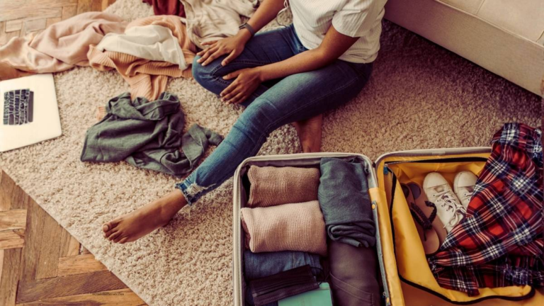 woman packing a suitcase neatly with folded clothes for a UK trip.