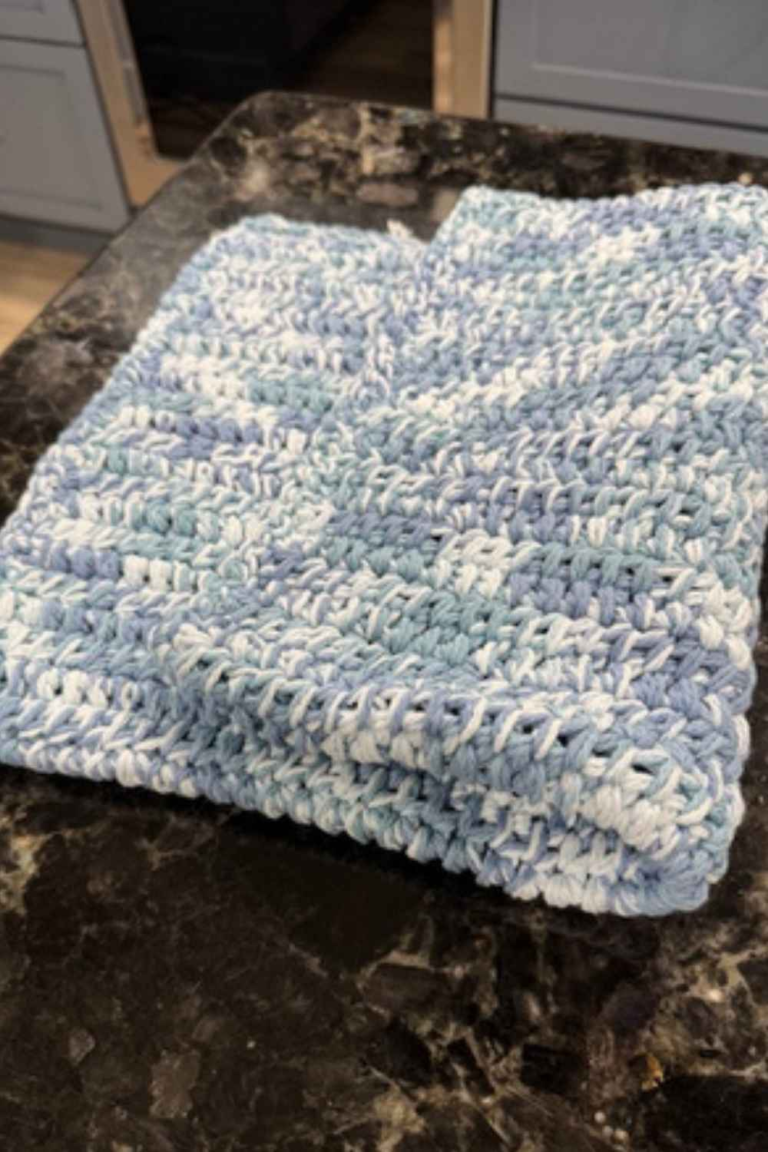 Corner detail of folded rectangular variegated blue crochet kitchen drying mat