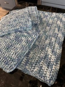 Coordinated crochet dishcloth, hot pad and drying mat laid out on kitchen countertop