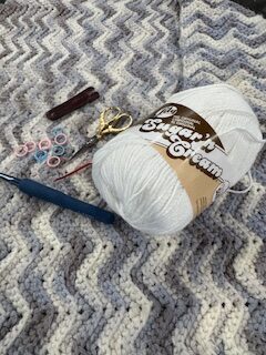 crochet tools for kitchen projects including yarn, hook, scissors, stitch markers and needle on crochet dishcloths.