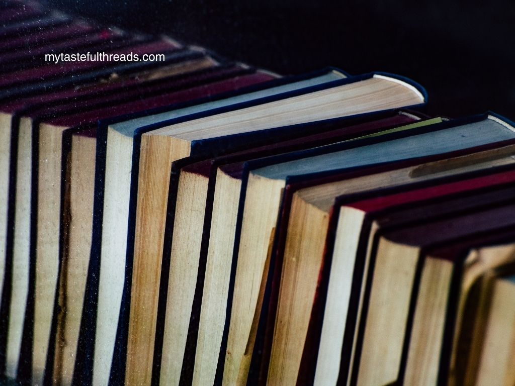 Row of well-read books with worn spines standing upright against a dark background