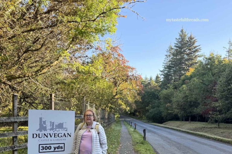 How to travel in Scotland without a car - Mary Ann standing by the Dunvegan Castle and Gardens sign walking towards Dunvegan Castle