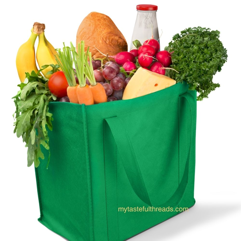 Green structured reusable grocery bag filled with bananas, radishes, grapes, and vegetables