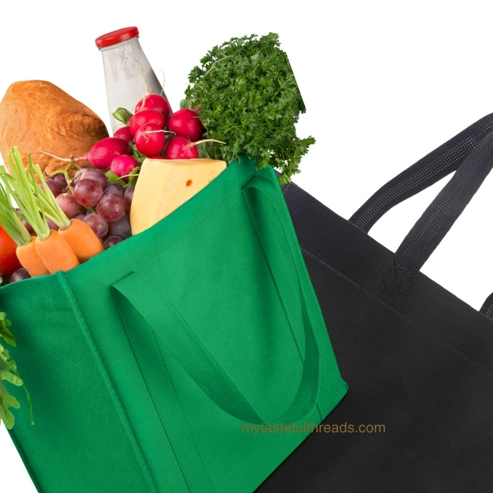 Close-up of green structured reusable grocery bag filled with groceries next to black canvas tote