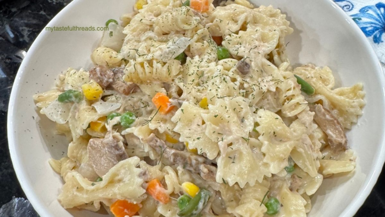 Creamy tuna casserole in white bowl with mixed vegetables and seasonings.